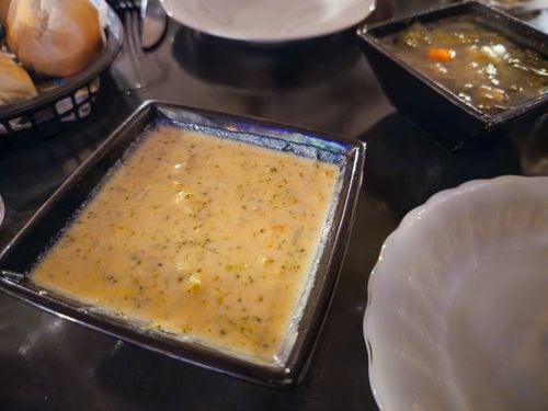 Two bowls of soup served in square bowls.