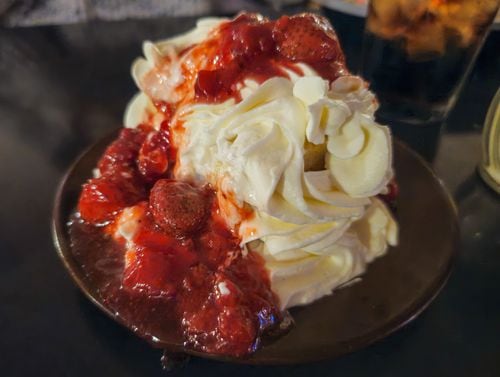 A slice of cake covered in whipped cream and strawberries.
