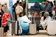 Ana Rosario of Houston, sitting left, tries to keep warm as she waits on her flight in Terminal A at Houston George Bush Intercontinental Airport Tuesday, Jan. 16, 2024, in Houston. (Melissa Phillip/Houston Chronicle via AP)
