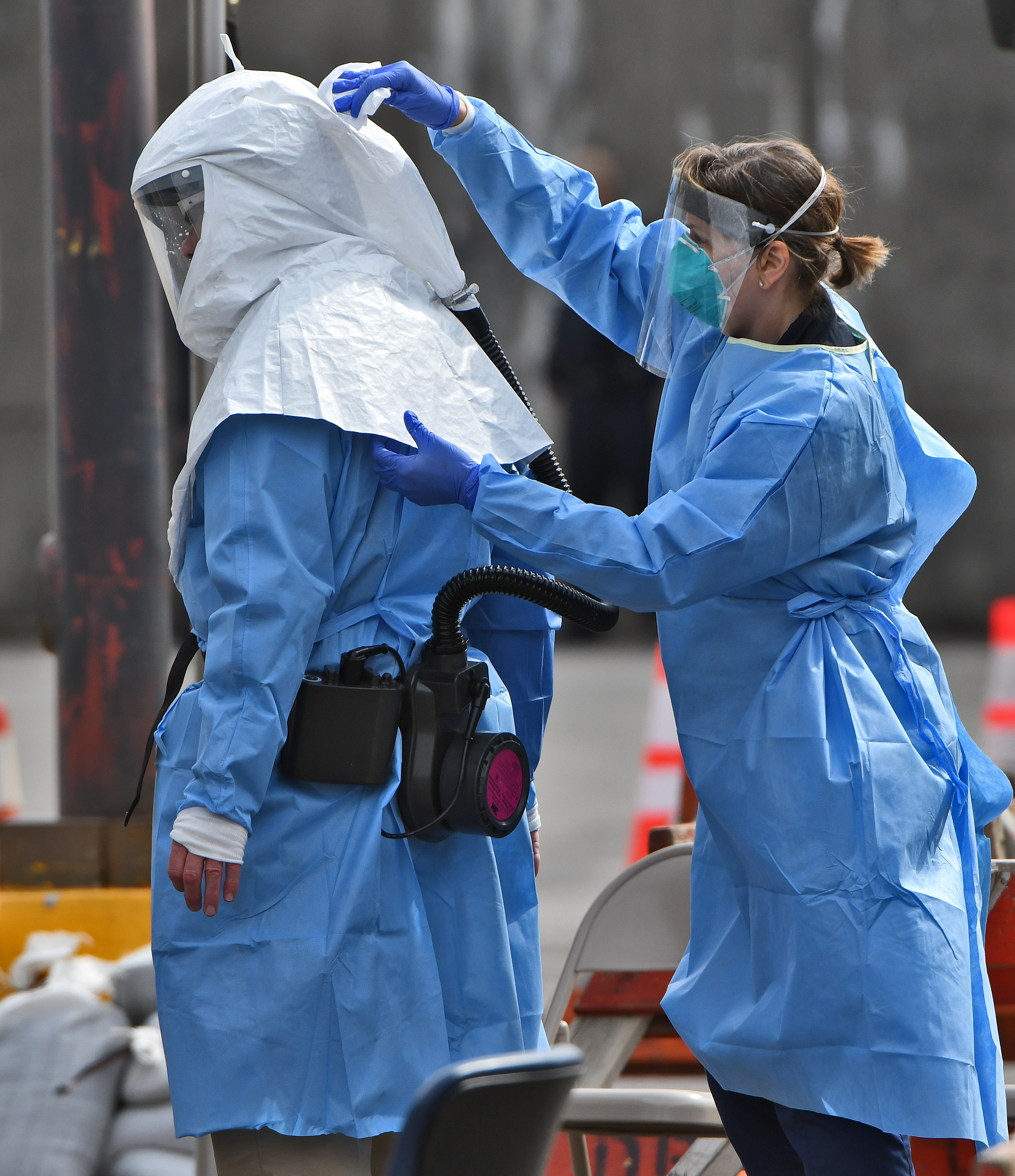 A woman wipes down a co-worker’s protective hood.  The Syracuse Community Health Center Covid 19 mobile test site, 819 S. Salina St., March 26, 2020.