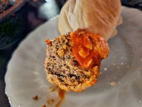 A cross section of a meatball topped in tomato sauce.