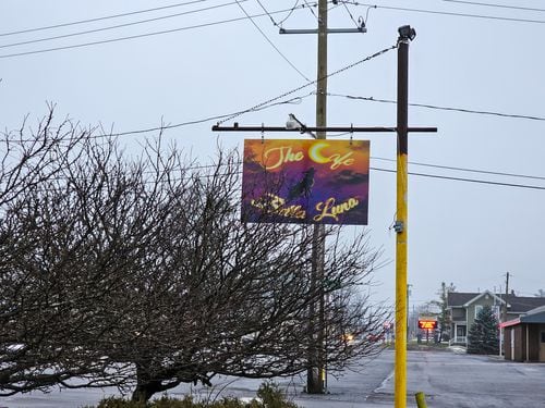 A sign that reads "The Cafe Bella Luna" hangs from a yellow post.