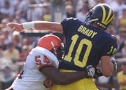 Syracuse University defensive end Dwight Freeney sacks University of Michigan quarterback Tom Brady for a 12-yard loss in the second quarter of their 1998 game in Ann Arbor, Michigan. The Orange beat the fifth-ranked Wolverines 38-28. (Photo by Johnathan Croyle | Syracuse.com)