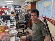 Htay Oo Win sits behind his desk at his grocery store, Golden Burma Asian Market, in Utica.